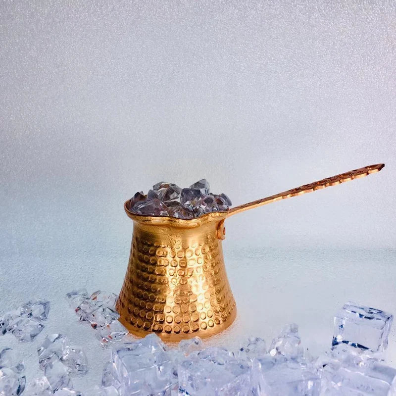 Copper Turkish Coffee Cezve heating over a campfire with steam rising from the spout