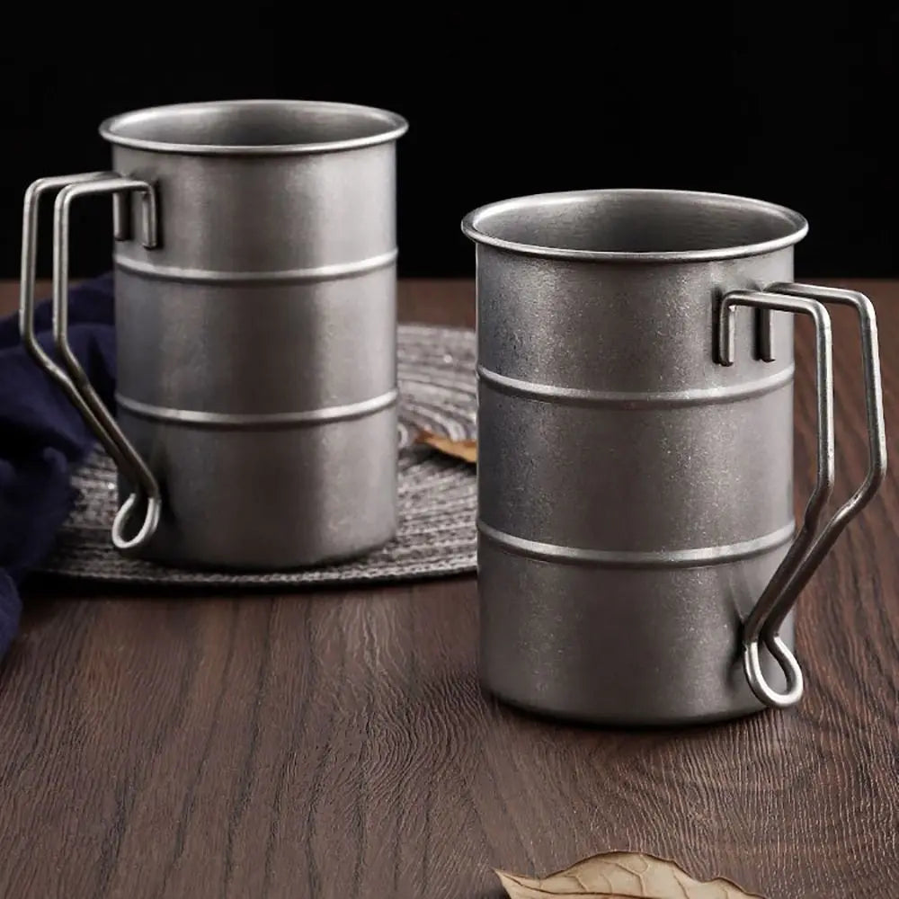 Vintage Oil Barrel Stainless Steel Camp Mug held in hand during outdoor camping, showing 350ml capacity and rugged design